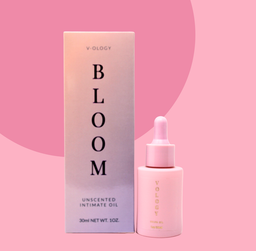 A bottle of Bloom Unscented Intimate Oil by V-OLOGY on a pink background.